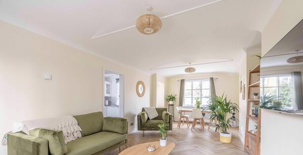 Een woonkamer met een bank, een salontafel, een eethoek met tafel en stoelen, en een keuken op de achtergrond.
