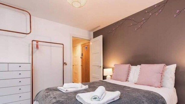 Een hotelkamer met een bed, een kledingkast, een deur en een muur met een takkenmotief.