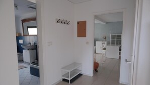 A modern, well-lit hallway with a white door, a white shelf unit, and a small window. - Quiet apartment for commuters & nature lovers - parking lot (Duisburg)