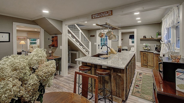 A spacious kitchen with a central island, wooden bar stools, and a staircase leading to another level. - Charming 4-bedroom farmhouse in Shady Valley, TN with breathtaking view (Shady Valley)