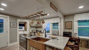 A kitchen with a large island, stainless steel appliances, and a view of the outdoors. - Charming 4-bedroom farmhouse in Shady Valley, TN with breathtaking view (Shady Valley)