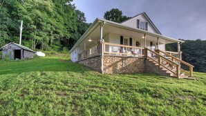 A house with a stone foundation, a porch, and a staircase leading to the entrance. - Charming 4-bedroom farmhouse in Shady Valley, TN with breathtaking view (Shady Valley)