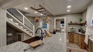 A kitchen with granite countertops, a wooden island, hanging pots, a staircase, and a view of the living area. - Charming 4-bedroom farmhouse in Shady Valley, TN with breathtaking view (Shady Valley)