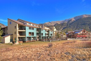 Un hôtel à plusieurs étages, doté de balcons et offrant une vue sur les montagnes.