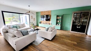 A modern living room with a sofa set, a coffee table, and a TV mounted on a brick wall. - Quiet villa with forest view  (Mios)