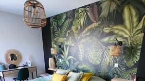A bedroom with a large bed, a desk, and a chair. There is a wall mural of tropical leaves. - Quiet villa with forest view  (Mios)