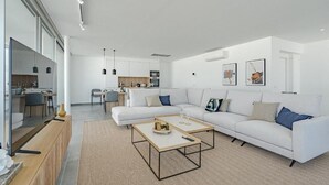 A modern living room with a white sofa, two coffee tables, and a kitchen in the background. - Villa Cala - Casangular by Upper (Adeje)