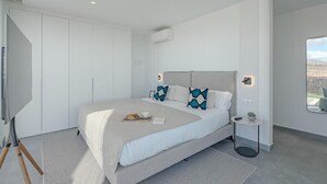 A modern bedroom with a large bed, a small bedside table, a mirror, and a view of the outdoors. - Villa Teresita - Casangular by Upper (Adeje)