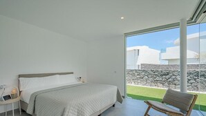 Une chambre avec un lit, une chaise et une vue sur un mur de pierre et la verdure environnante.