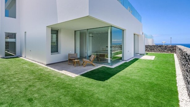 Une maison moderne dotée d’une porte vitrée donnant sur un patio aménagé avec du mobilier d’extérieur.