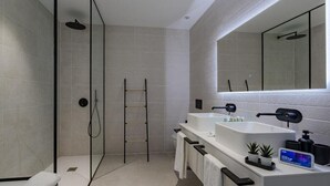Une salle de bain moderne avec une douche à l’italienne en verre, un meuble-lavabo double et un grand miroir au-dessus du meuble.
