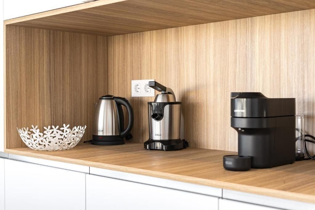 A kitchen counter with a coffee maker, a kettle, and a basket.