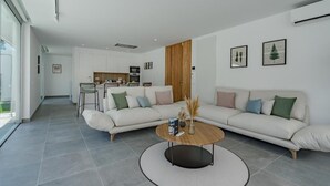 A modern living room with a large L-shaped sofa, a coffee table, and a kitchen in the background.