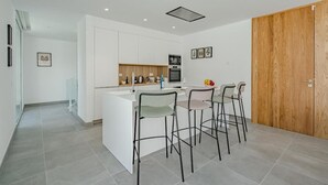 A modern kitchen with white cabinetry, a central island, and bar stools.