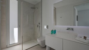 A modern bathroom with a glass-enclosed shower, a white sink, and a large mirror.