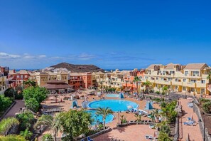 Ein Resort mit mehreren Schwimmbecken, einem zentralen Platz und Gebäuden mit Balkonen.