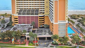A multi-story hotel with a pool, parking garage, and a beach view. - Caravelle Resort 606 (Myrtle Beach)
