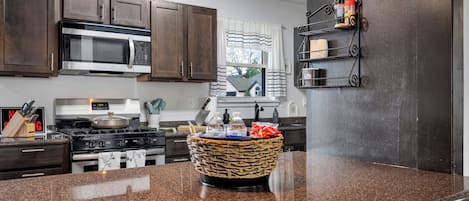 A kitchen with dark wooden cabinets, a stainless steel microwave, a gas stove, and a granite countertop.