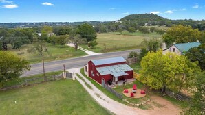 A rural property with a red barn, a dirt path, and a fenced area with outdoor seating. - Private and Historic Rocking Ox Ranchette & Estate (Fredericksburg)