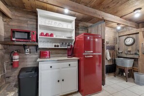 A compact kitchen with a red refrigerator, white cabinets, a microwave, and a coffee maker. - Private and Historic Rocking Ox Ranchette & Estate (Fredericksburg)