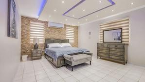 A bedroom with a bed, nightstand, dresser, and a wall-mounted air conditioner.