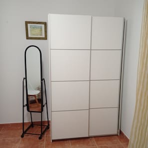 A white wardrobe with a grid pattern, a black metal chair, and a framed picture on the wall.