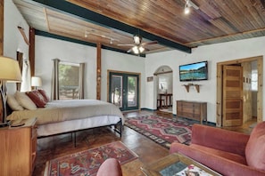 A bedroom with a bed, a desk, a chair, a TV, and a door. - Willows Retreat-Sleeps 17, Hot-Tubs,4 Mins to Main (Fredericksburg)