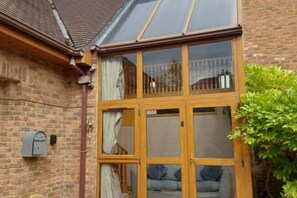 A conservatory with a wooden frame, a brick wall, and a mailbox. - Tower House
 (Helen's Bay)