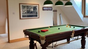 A pool table with a green felt surface, a framed photograph on the wall, and a window with a view of trees. - Tower House
 (Helen's Bay)