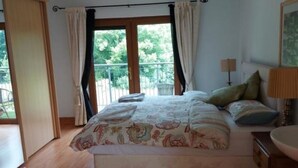 A bedroom with a bed, curtains, a window, and a view of greenery outside. - Tower House
 (Helen's Bay)