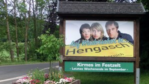 A billboard with a family and text in German advertising a festival in Hengerschied.