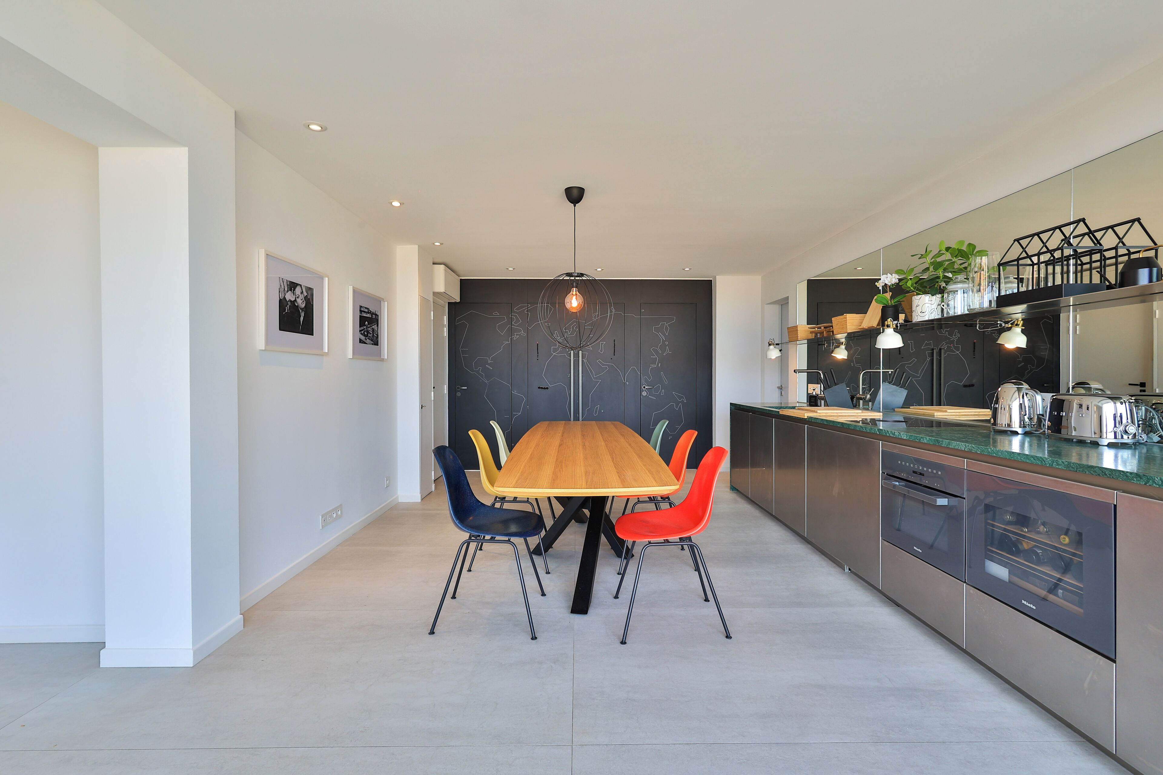 Una cocina moderna con una mesa de comedor de madera, sillas coloridas y electrodomésticos de acero inoxidable.