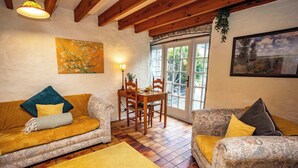 Un accogliente soggiorno con due divani decorati, un tavolo da pranzo in legno e un'ampia finestra con vista su aree verdi.