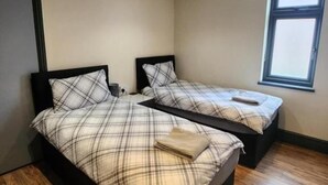 Un dormitorio con dos camas, suelo de madera y una ventana.