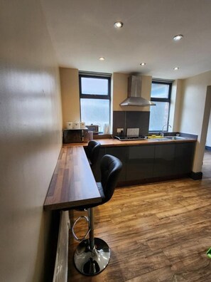 Una cocina moderna con una mesa de comedor de madera y un taburete negro, horno empotrado y un ventanal grande.