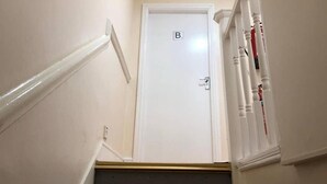 Una escalera con barandillas blancas y una puerta cerrada marcada con una 'B'.
