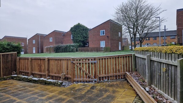 A residential area with brick houses, a wooden fence, and a paved driveway.