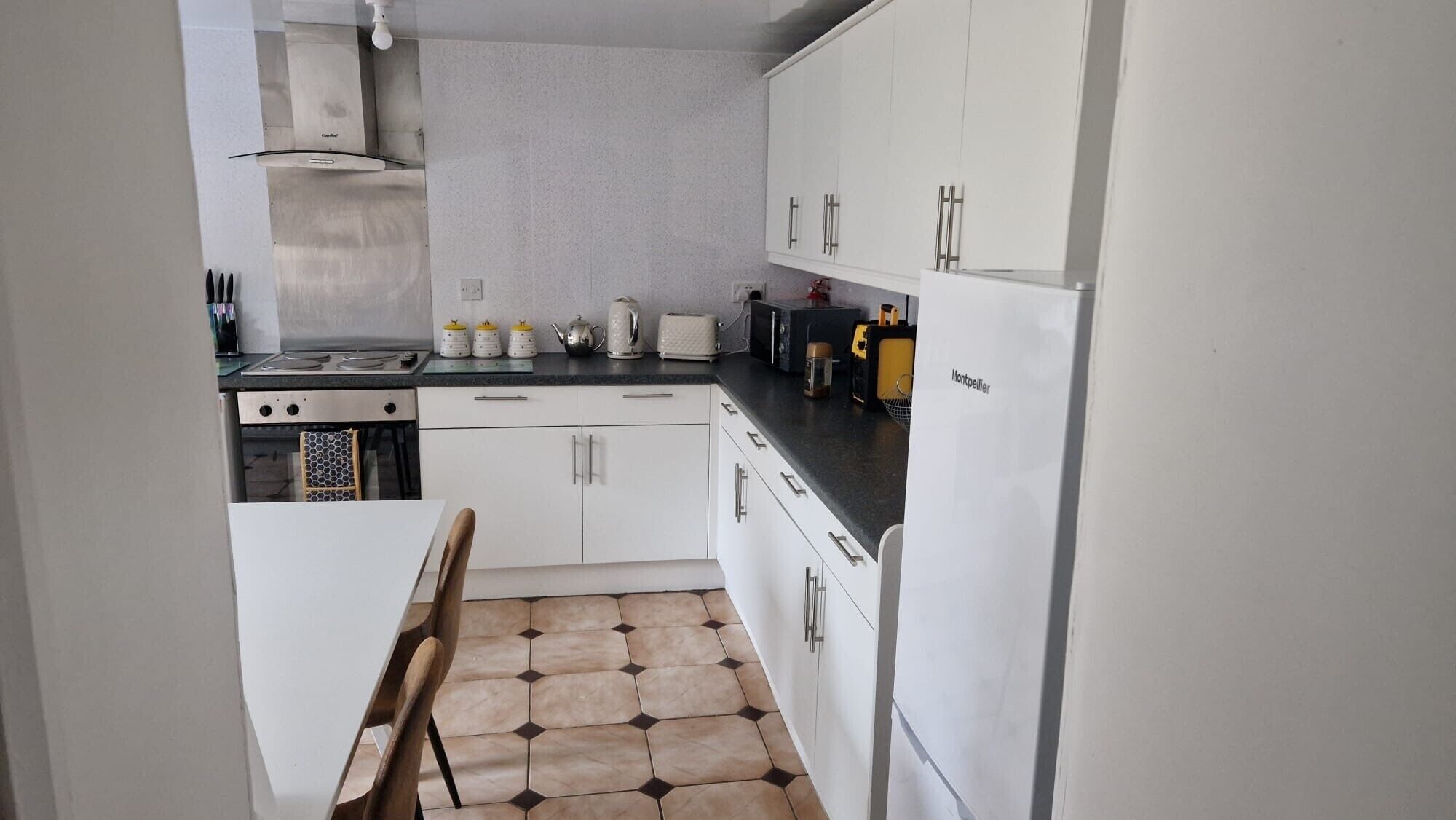 A compact kitchen with white cabinets, a gas stove, a microwave, and a coffee maker.