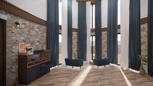 Une pièce avec un mur en pierre, un plancher en bois, un canapé de couleur sombre, un meuble en bois et des rideaux bleus.