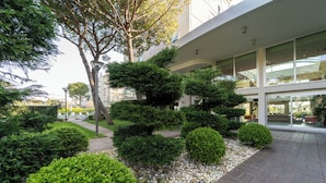 Un edificio moderno con jardín ajardinado, arbustos podados y un sendero de grava.
