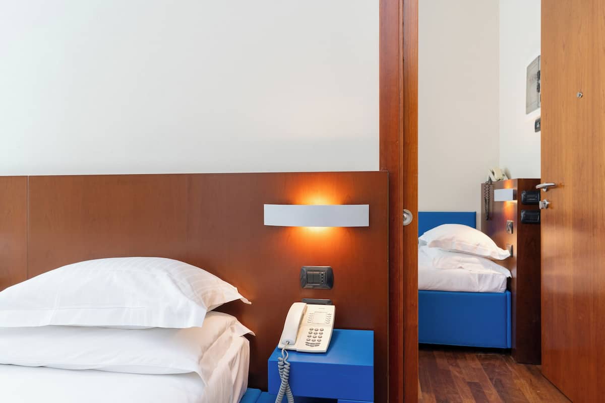 A hotel room with a wooden headboard, a bedside telephone, and a blue nightstand.