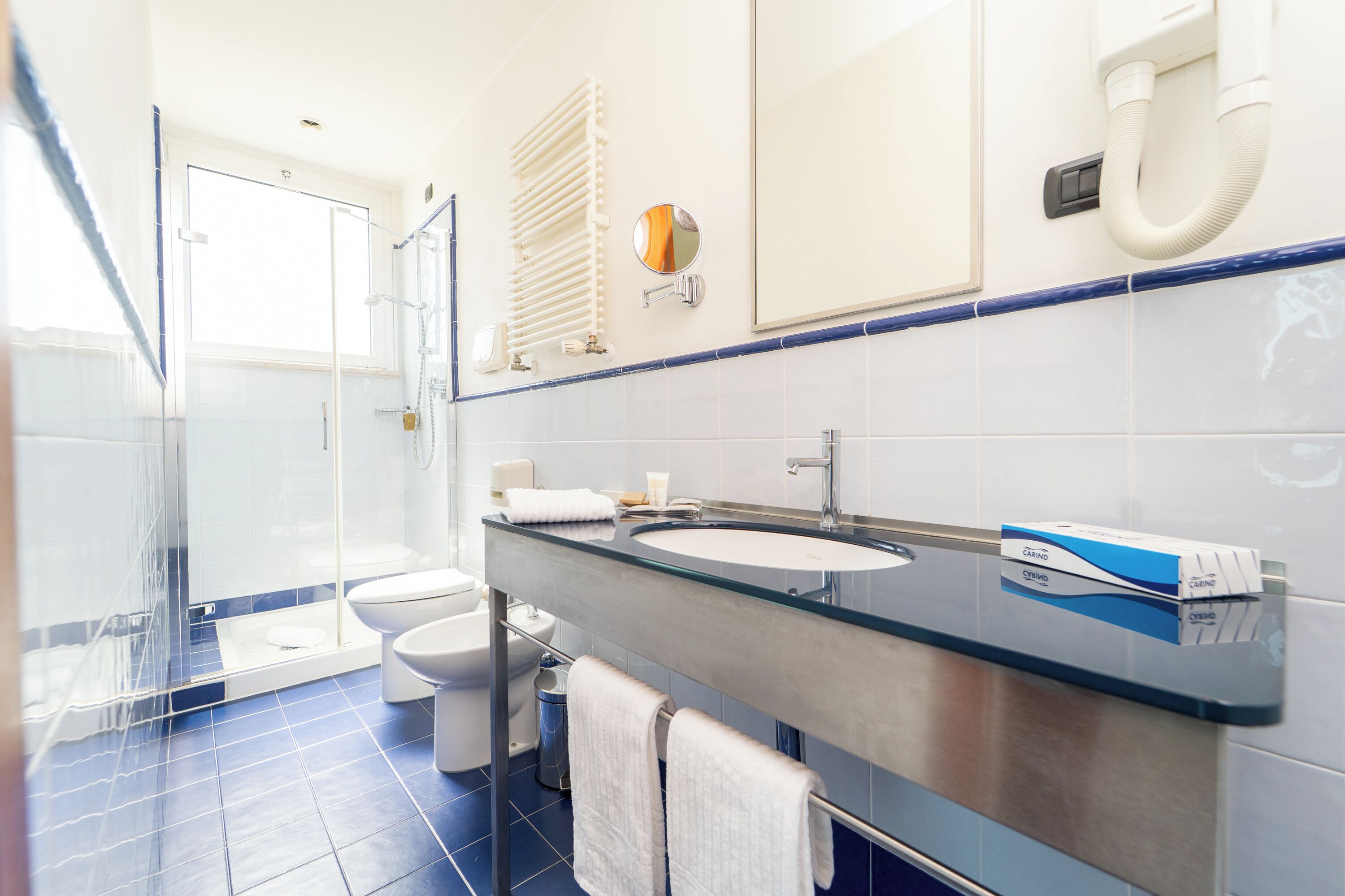 A modern bathroom with a glass shower enclosure, a toilet, a sink with a mirror, and a towel rack.