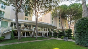 Un edificio moderno con fachada curva, un patio central con césped y árboles.