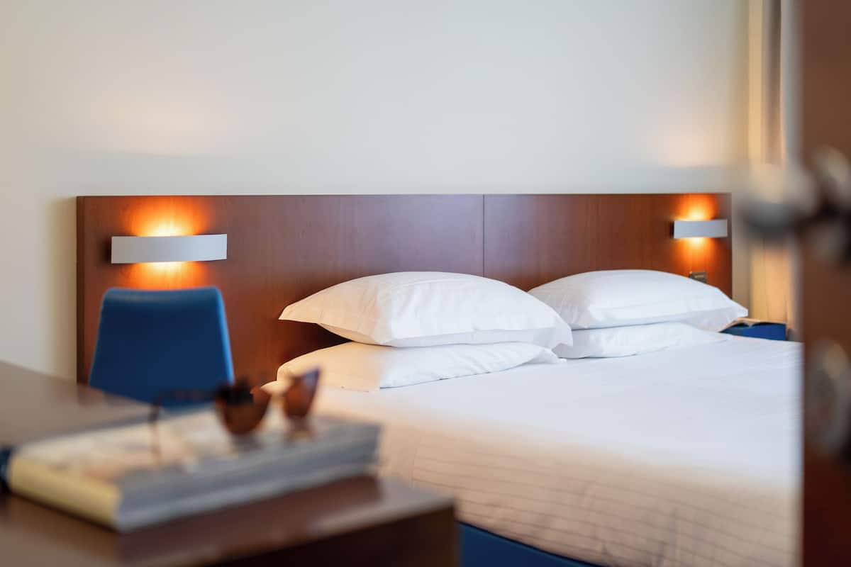A hotel room with a bed, two bedside tables, a desk, and a chair.