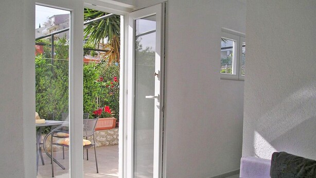 Une pièce dotée d’une porte-fenêtre coulissante donnant sur un patio extérieur aménagé avec une table et des chaises.