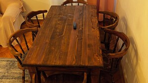 A wooden dining table with six chairs, a clock on the wall, and a window with curtains. - Suite 49 (Brasov)