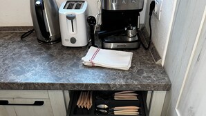 A kitchen with a marble countertop, a coffee maker, two toasters, and a drawer organizer with utensils. - Suite 49 (Brasov)