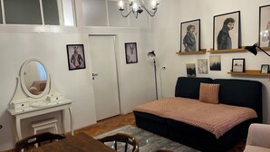 A bedroom with a bed, a desk with a mirror, a dresser, a chandelier, and wall art. - Suite 49 (Brasov)