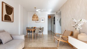 A modern living room with a sofa, dining table, chairs, and a decorative vase with flowers.