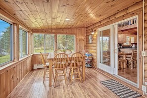 L’intérieur d’un chalet en bois comprend un coin repas, de grandes fenêtres et une vue sur l’extérieur.